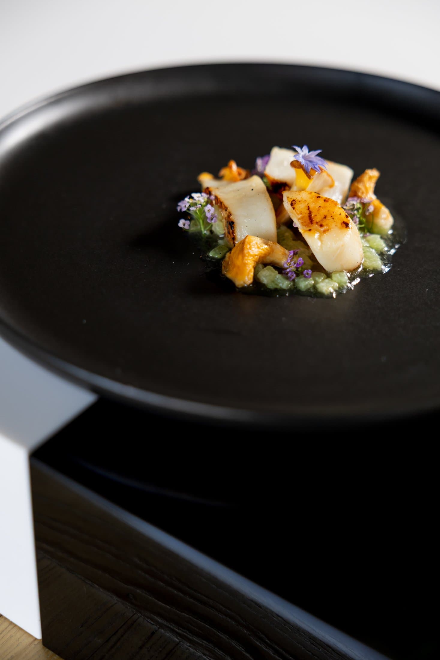 Plated seared scallops with chanterelles and edible flowers